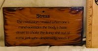 Front of wooden plaque showing humorous stress definition and scale for size