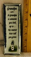 Front of glass plaque showing poem and lighthouse graphic with ruler for scale