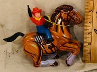 Left side view of cowboy on horse showing litho details and scale against ruler