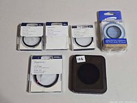 Six camera UV filters laid out, showing packaging and loose filter