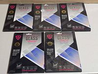 Five boxed iShieldz glass screen protectors side by side