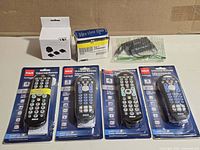Overall lot showing four RCA remotes in blister packs, Vital travel adapter box, Jensen voltage converter box, loose adapter in plastic sleeve