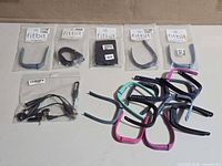 Lot overview showing sealed Fitbit bands, loose bands and cables