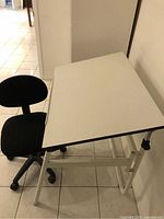 Drafting table angled with office chair positioned beside