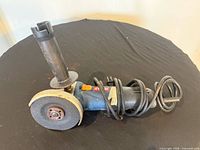 Full view of Ryobi angle grinder with side handle and disc