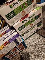 Stack of three FoodSaver vacuum roll boxes beside Seal-a-Meal boxes