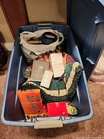 Overall view inside storage tote showing tree skirt, saucepan, Hershey box, and other boxed items