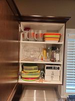 Cabinet view with plates, bowls, mugs, serving utensils, pitcher and shakers