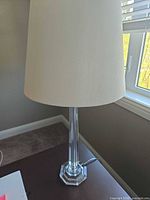 Full view of lamp showing clear column, base, and white drum shade
