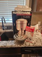Group shot of boxed coffee urn, boxed rosette set, and stainless steel fluted mold with lid
