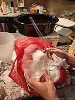 Cup, ladle and wrapped glass items inside red bag