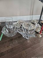 Overall view of glass bowls, hurricane vase, silver-plated dishes, candlesticks and candles on floor