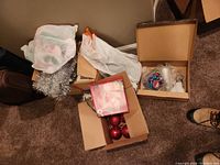 Overview of boxes containing red ornaments, tinsel, topper and multicolor ornaments
