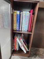 Open cabinet showing two shelves of cookbooks