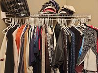 Overview of clothing lot on hangers showing variety of pieces and colours