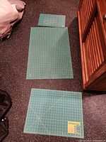 Three green cutting mats of different sizes laid out on floor
