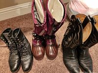 Front view three pairs boots upright on carpet