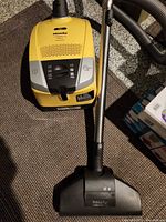Yellow Miele Compact C2 canister vacuum with wand and powered floorhead visible