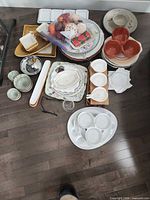 Overall view of all dinnerware and serveware pieces laid out on floor