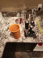 Overview showing glass pitchers, terracotta pot, electric wine opener on base, stainless-steel ice bucket and small cups