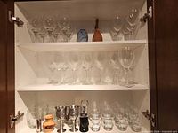 Cabinet view showing multiple wine glasses, vases and metal goblets