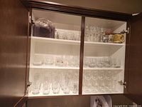 Cabinet shelves showing variety of glassware types and quantities