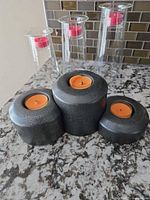 Front view showing three ceramic tealight holders with orange candles