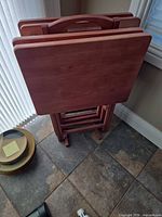 Front view of nested cherry wood folding TV trays in stand