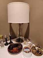 Overall lot showing lamp, candlesticks, plates, candles, accessory container and figurine
