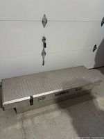 Closed tool box showing exterior diamond-plate aluminum and latch