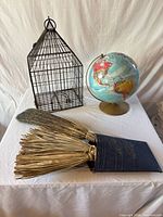 Overall shot showing wire bird cage, globe on stand, tin wall pocket with brooms