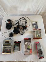 Overall lot showing calculators, Nyrius units, boxed caller ID, and sealed accessories