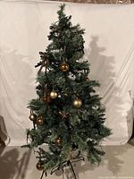 Full view of 5-foot artificial Christmas tree with some ornaments and ribbons attached
