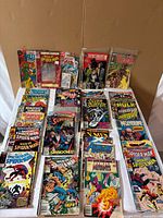 Tabletop view of stacked and standing comic books showing assorted Marvel and DC titles