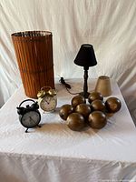 Group shot showing basket, lamp with black shade, tan shade, two clocks and eight bun feet