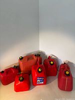 Front view of six red plastic gasoline cans displaying varying sizes and caps