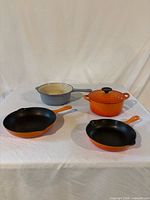 Four Le Creuset cookware pieces on table