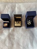 Three rings displayed in open boxes on fabric surface