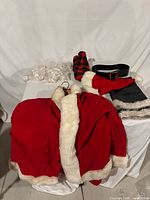 All costume components laid out: jacket, pants, belt, scarf, mittens, beard