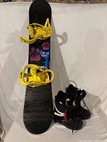 Snowboard with bindings and pair of boots displayed together
