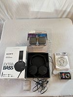 Sony headphones with box, Pentax camera with CD and Terk extender displayed on tabletop