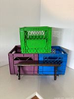 Stacked purple, blue, green plastic crates with wooden shelf front view