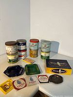 Group shot of tobacco tins, ashtrays, cigar box and advertising box on counter
