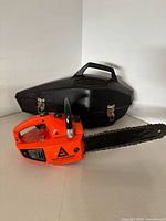 Chainsaw resting in front of black carry case