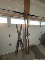 Two pairs of vintage wooden skis leaning against garage door