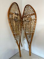 Full view of both wooden snowshoes leaning against wall