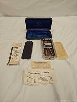 Full set opened showing case, razor, hone cover, papers