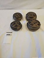 Four brass hand warmers top view showing size and lid patterns