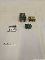 three enamel brass boxes beside lot card