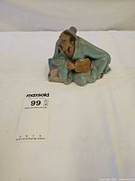 Front view of glazed clay mudman figurine with lot number card